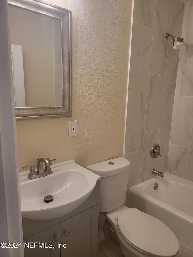 bathroom with toilet, a textured wall, shower / washtub combination, and vanity