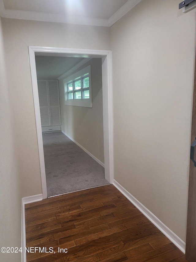 hall featuring dark wood-type flooring, crown molding, and baseboards