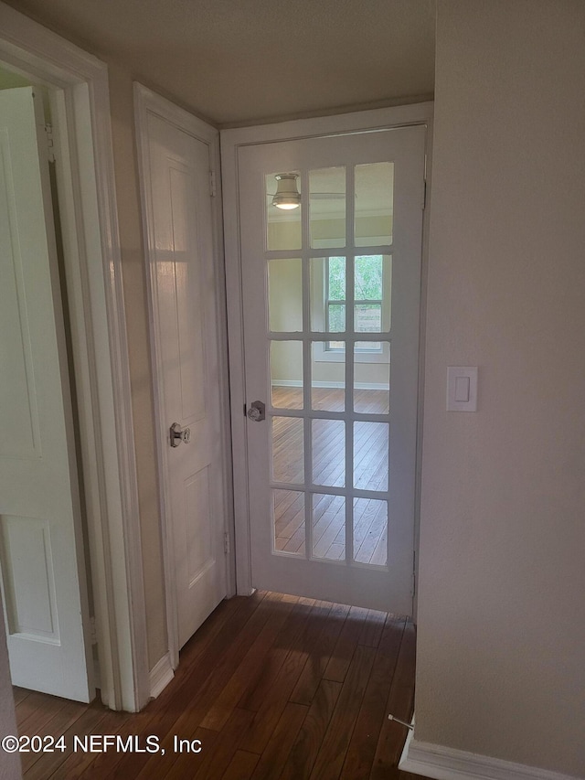 doorway featuring dark wood-type flooring and baseboards