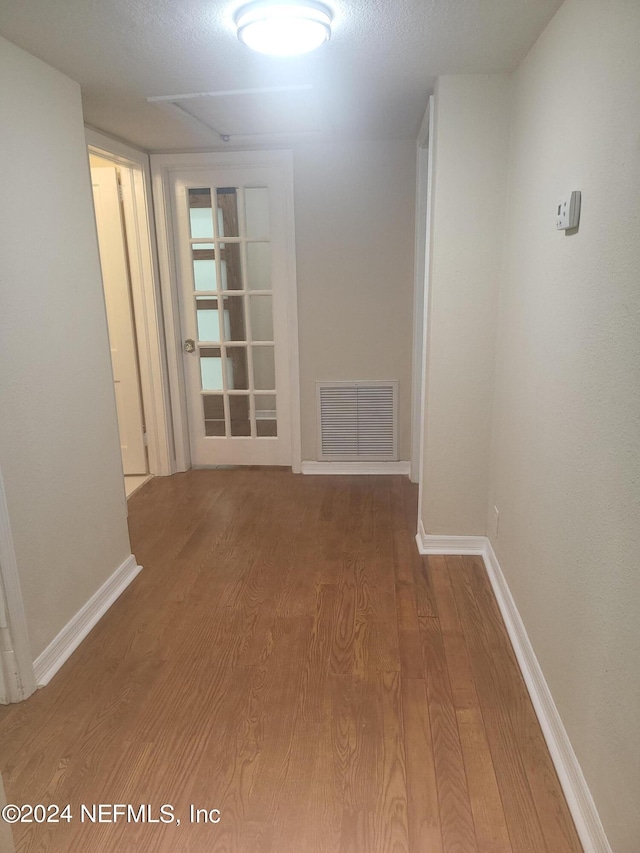 hallway with hardwood / wood-style flooring and a textured ceiling