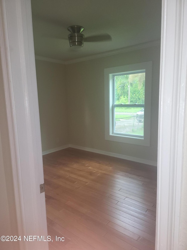 spare room with light wood-style floors, baseboards, and crown molding