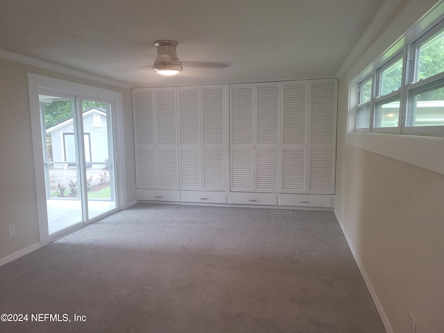 spare room with crown molding, baseboards, ceiling fan, and carpet flooring