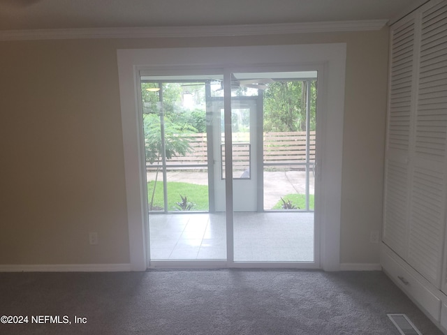 doorway with crown molding, plenty of natural light, and carpet flooring