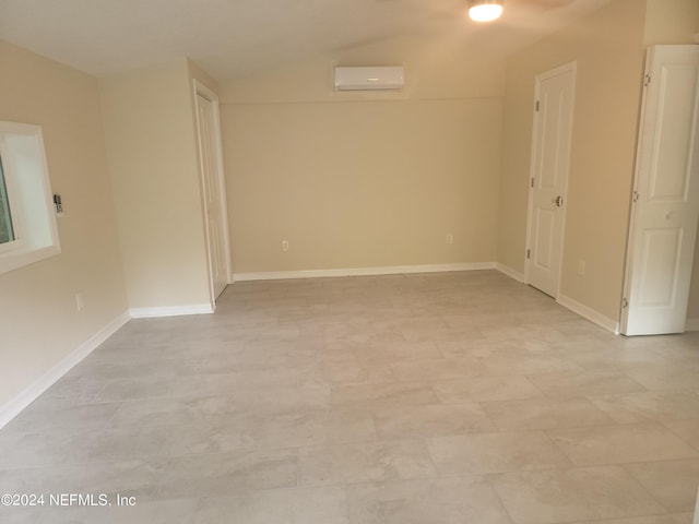 spare room featuring vaulted ceiling and an AC wall unit