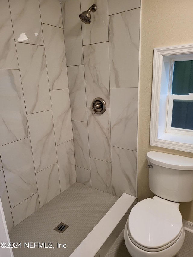 bathroom featuring toilet and a tile shower