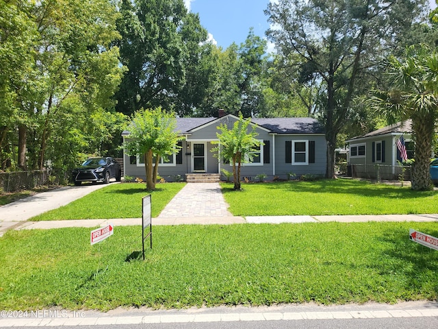 view of front facade with driveway, fence, and a front lawn