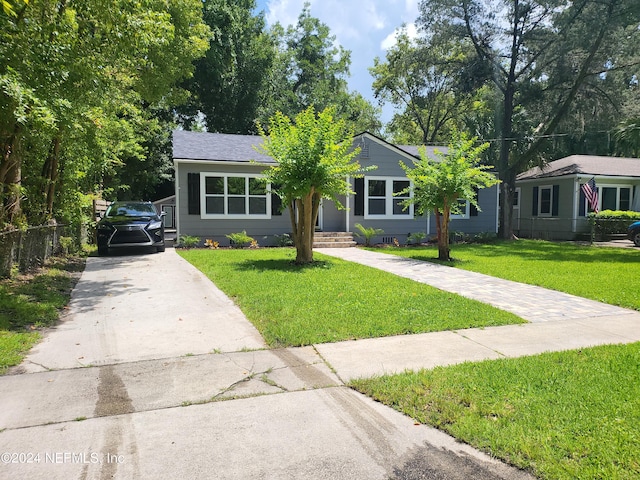 ranch-style house with concrete driveway, fence, and a front lawn