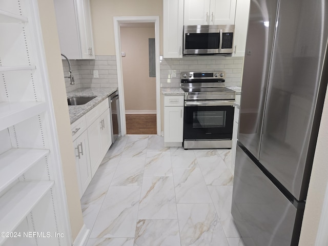 kitchen with light stone counters, marble finish floor, appliances with stainless steel finishes, white cabinetry, and a sink