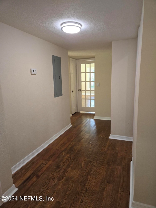 corridor featuring dark hardwood / wood-style flooring, electric panel, and a textured ceiling