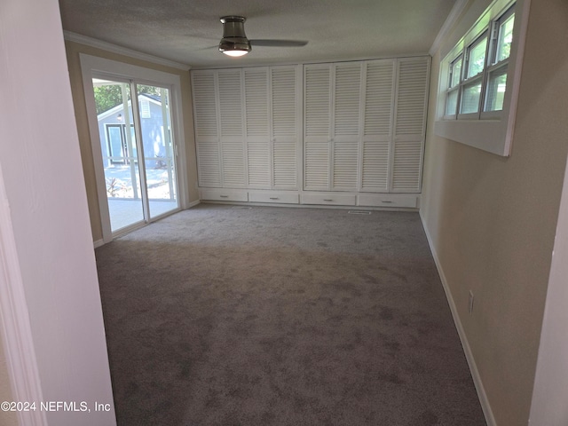 carpeted spare room with crown molding, plenty of natural light, and a textured ceiling