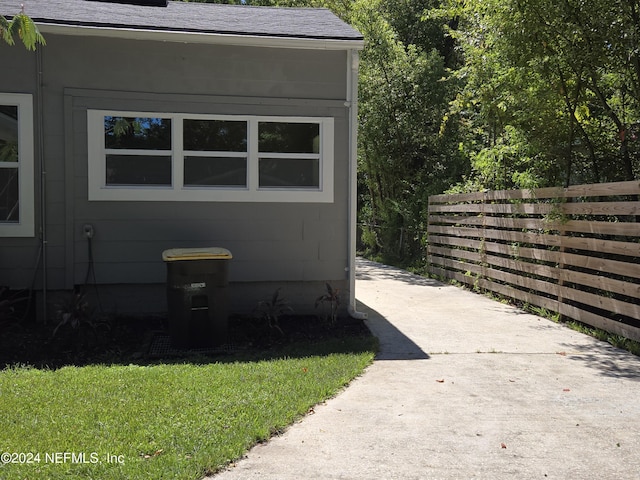 view of side of home with a shingled roof and fence