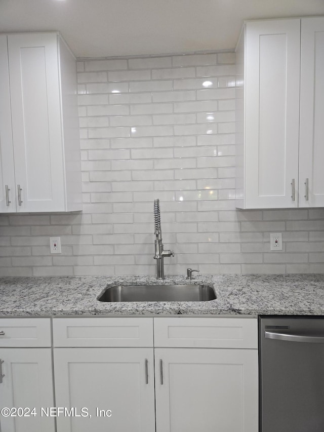 kitchen with dishwasher, decorative backsplash, a sink, and white cabinets