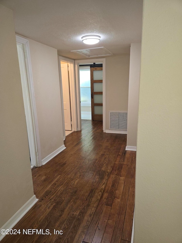 hallway featuring dark wood-type flooring and a textured ceiling