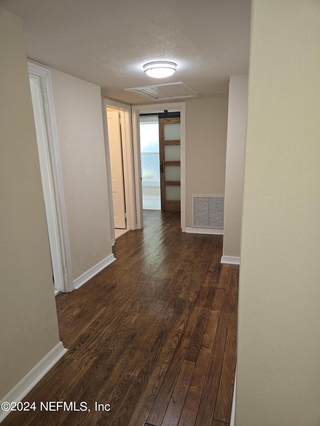 corridor with dark wood-style floors, baseboards, visible vents, and a textured ceiling