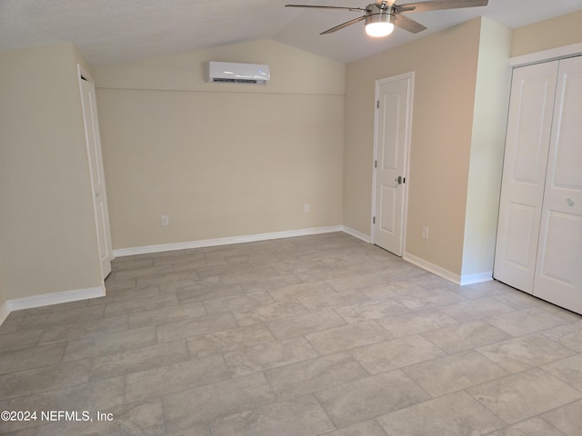 unfurnished bedroom featuring lofted ceiling, an AC wall unit, and baseboards