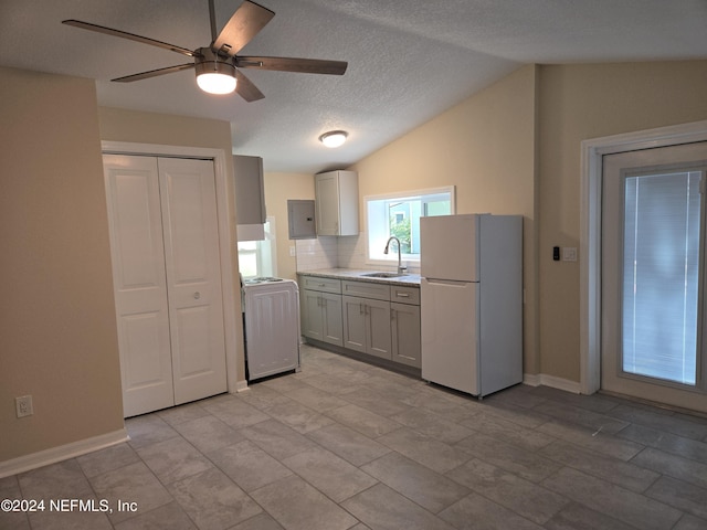 kitchen with electric panel, washer / clothes dryer, freestanding refrigerator, vaulted ceiling, and a sink