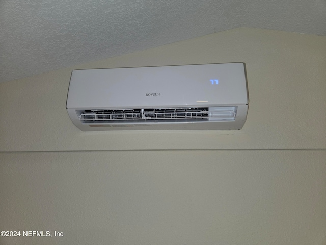 room details featuring a wall mounted air conditioner and a textured ceiling