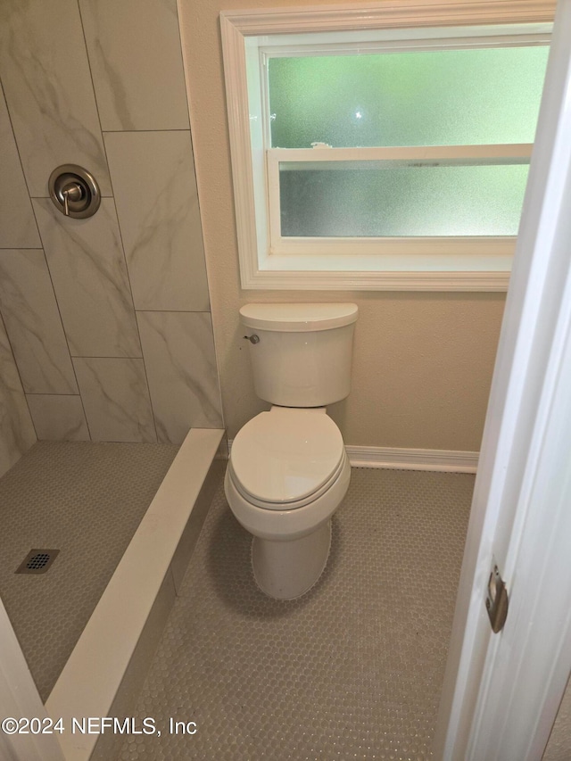 bathroom featuring tile patterned floors, toilet, and tiled shower