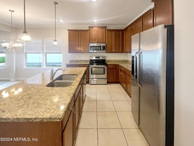 kitchen featuring pendant lighting, a center island with sink, sink, appliances with stainless steel finishes, and a chandelier