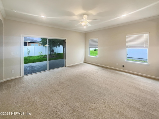 empty room featuring ceiling fan, plenty of natural light, ornamental molding, and light carpet