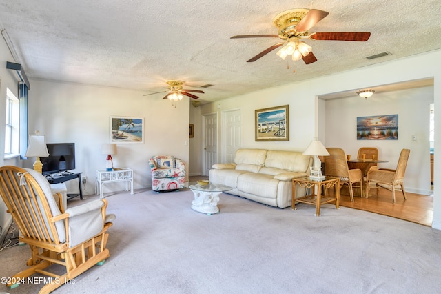 carpeted living room with a textured ceiling and ceiling fan