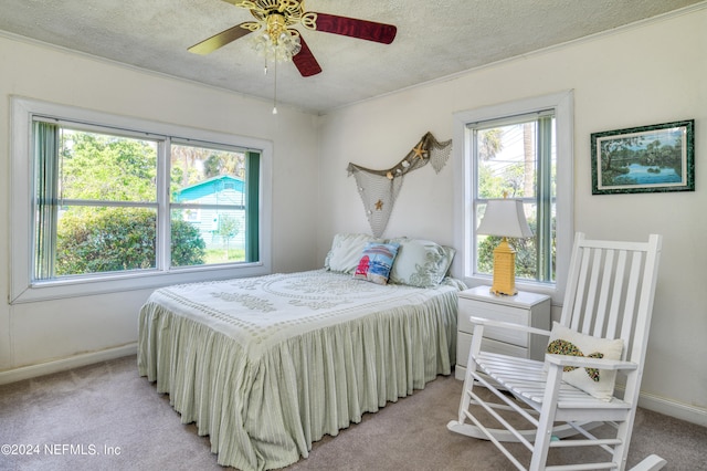 carpeted bedroom featuring multiple windows, a textured ceiling, and ceiling fan