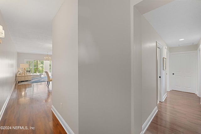 hallway featuring a chandelier and wood-type flooring