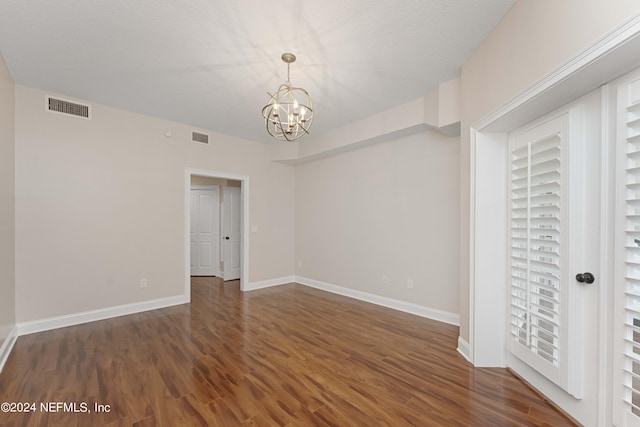 unfurnished bedroom featuring dark wood-type flooring and a chandelier