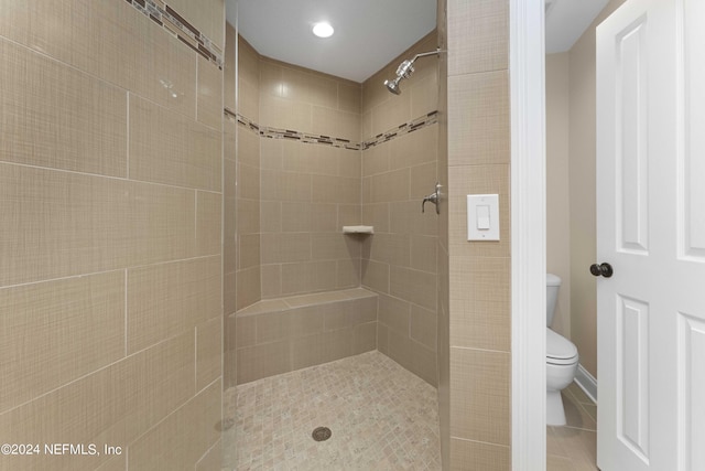 bathroom featuring tile patterned floors, toilet, and tiled shower