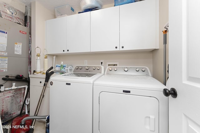 laundry room featuring cabinets, a textured ceiling, heating unit, and washer and clothes dryer