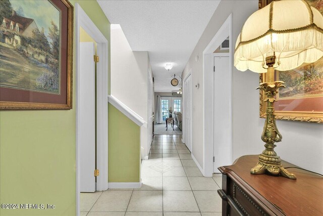 hall featuring a textured ceiling and light tile patterned floors