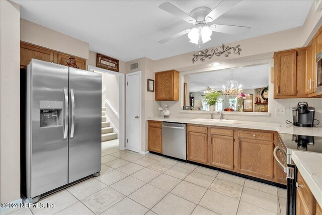 kitchen with light tile patterned flooring, sink, ceiling fan with notable chandelier, and stainless steel appliances