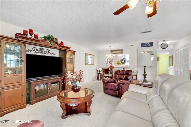 living room featuring a textured ceiling, carpet flooring, and ceiling fan with notable chandelier