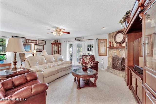 living room featuring ceiling fan, a fireplace, light carpet, and a textured ceiling