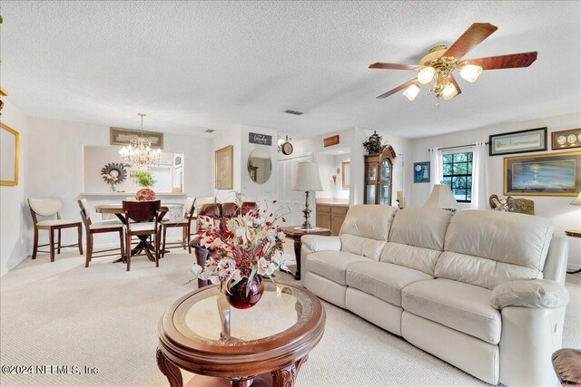 living room with a textured ceiling, light carpet, and ceiling fan with notable chandelier