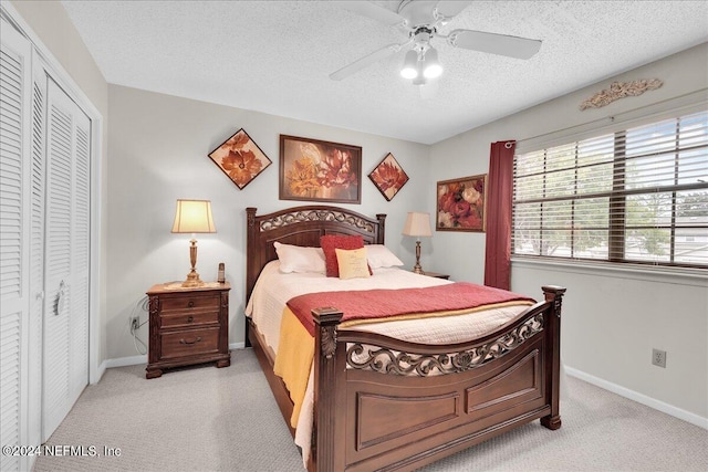 bedroom featuring a closet, a textured ceiling, light colored carpet, and ceiling fan