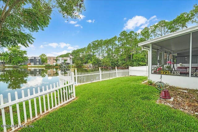 view of yard with a sunroom and a water view