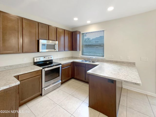 kitchen with kitchen peninsula, sink, light tile patterned floors, and stainless steel appliances