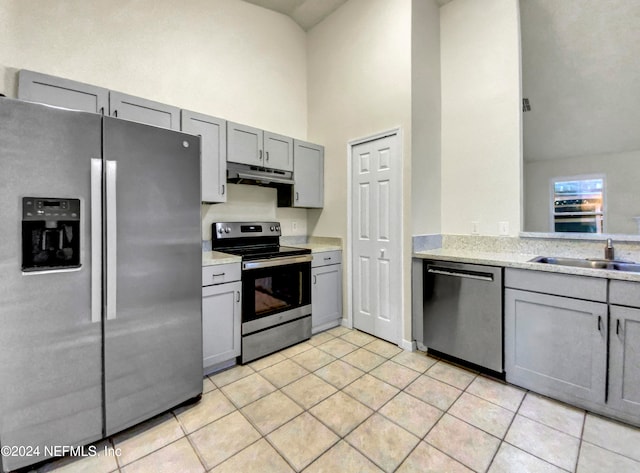 kitchen with gray cabinets, stainless steel appliances, sink, and high vaulted ceiling