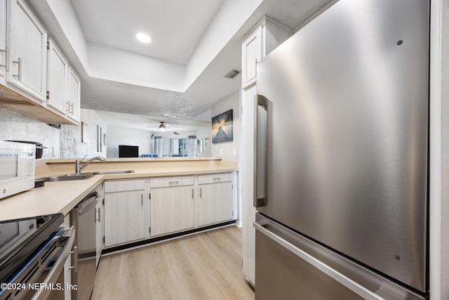 kitchen featuring appliances with stainless steel finishes, light wood-type flooring, ceiling fan, sink, and white cabinets