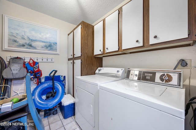 washroom featuring cabinets, independent washer and dryer, a textured ceiling, and light tile patterned flooring