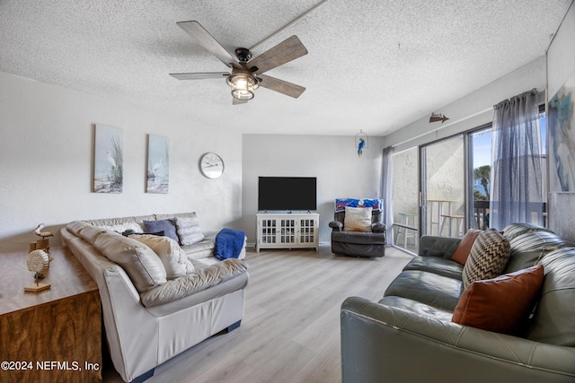 living room featuring ceiling fan, light hardwood / wood-style flooring, and a textured ceiling