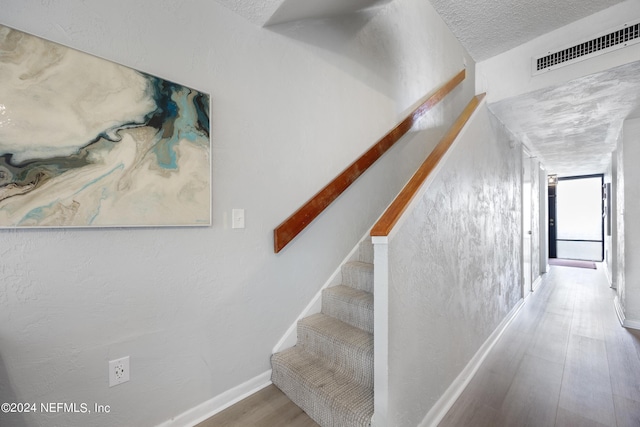 stairs with hardwood / wood-style flooring and a textured ceiling