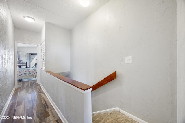 hall with a textured ceiling and hardwood / wood-style flooring