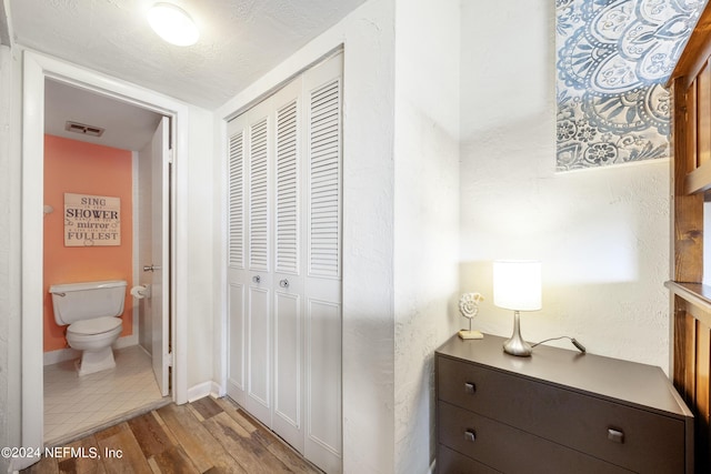 bedroom featuring ensuite bathroom, a closet, and light hardwood / wood-style flooring