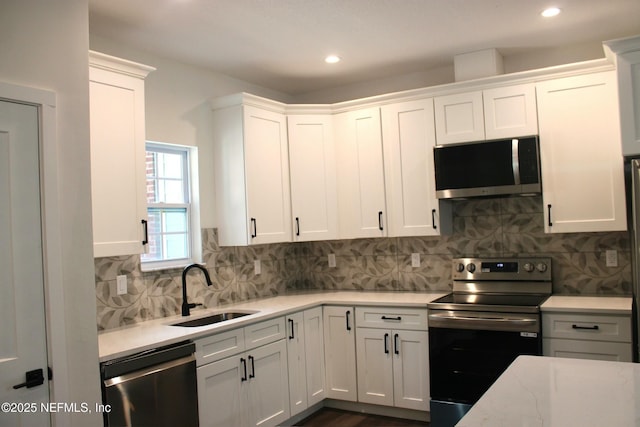 kitchen featuring a sink, stainless steel appliances, tasteful backsplash, recessed lighting, and white cabinets