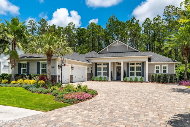 view of front of house with a garage, stone siding, decorative driveway, and a front yard