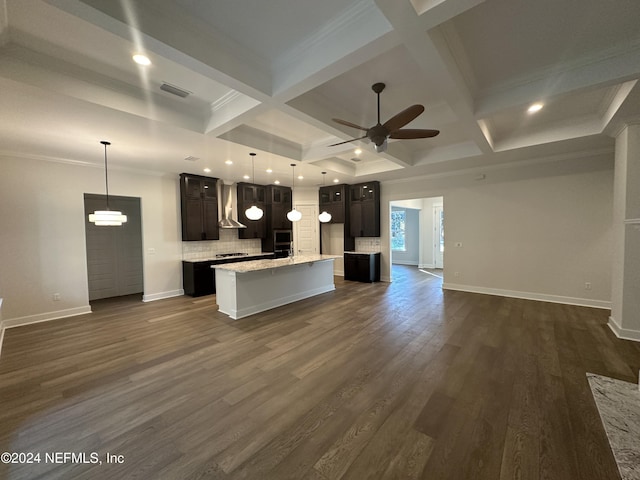 kitchen with a center island, dark wood-type flooring, coffered ceiling, wall chimney range hood, and crown molding