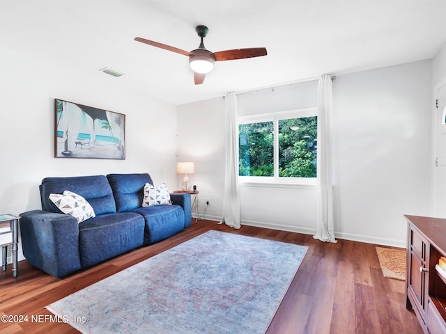 living room featuring dark wood-type flooring and ceiling fan