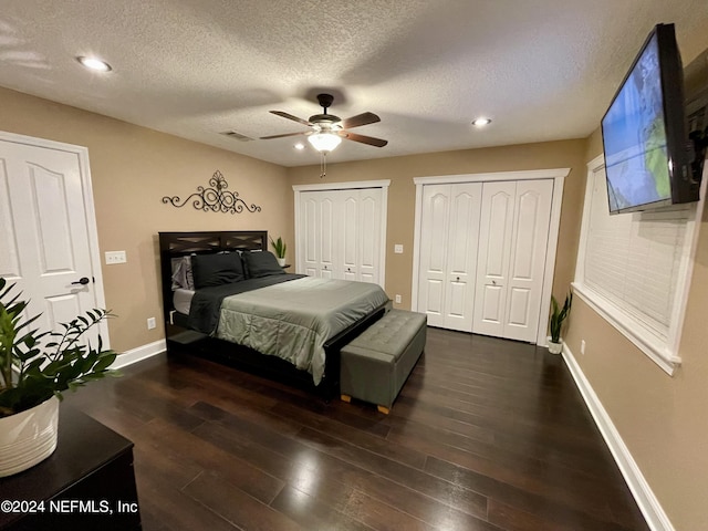 bedroom featuring a textured ceiling, ceiling fan, two closets, and dark hardwood / wood-style floors